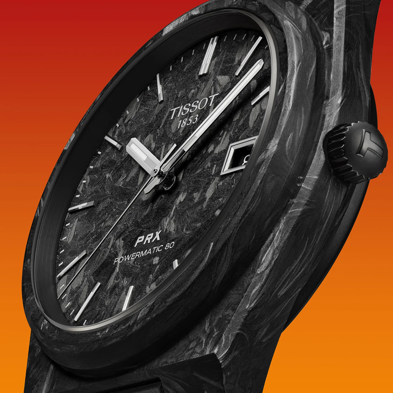 Tissot PRX Powermatic 80 Carbon 40mm Uhr vor einem farbigen Hintergrund